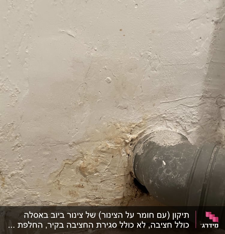 צינור אפור מחובר לקיר עם סימני רטיבות